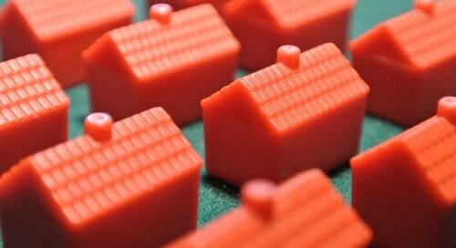 Red,plastic,monopoly,houses,hotels,on,green,background