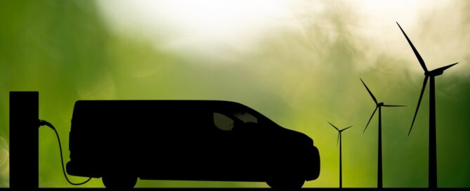 Silhouette,of,electric,van,with,charging,station,and,wind,turbines