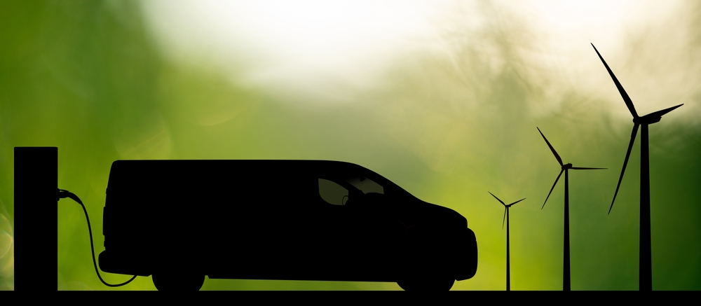 Silhouette,of,electric,van,with,charging,station,and,wind,turbines