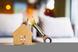 Wooden,house,model,with,metal,wrench,symbolizing,home,maintenance,,repair
