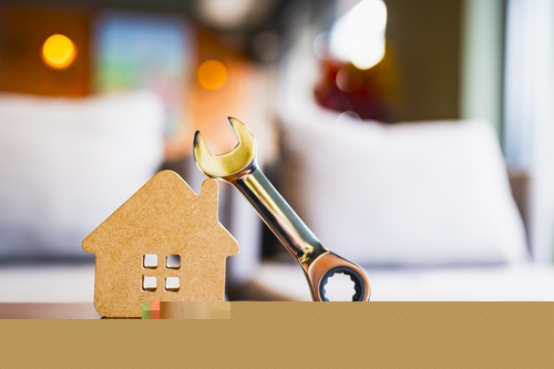 Wooden,house,model,with,metal,wrench,symbolizing,home,maintenance,,repair